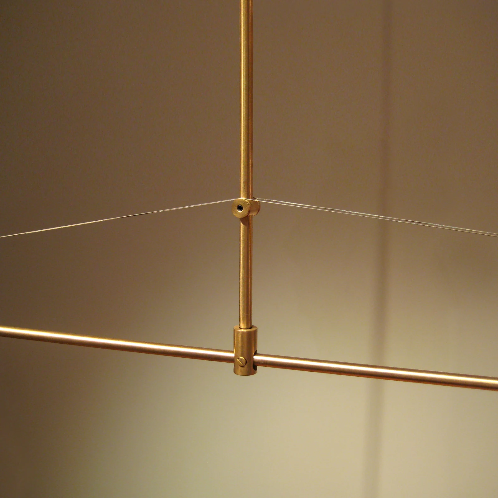 Close detail of a brass joint and tensioned wire within a lighting structure
