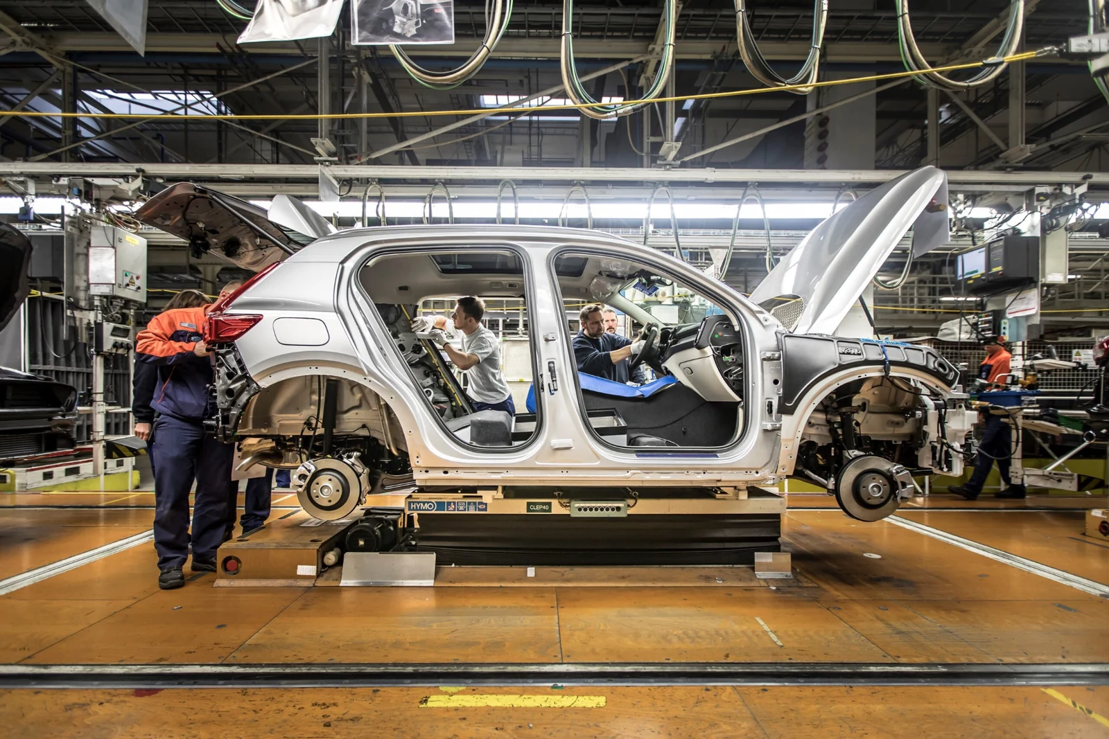 A Volvo body shell on the production line with technicians fitting the interior